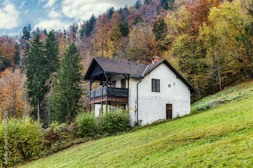Old traditional house with a view in Slovenian Alps surrounded by high colorful trees