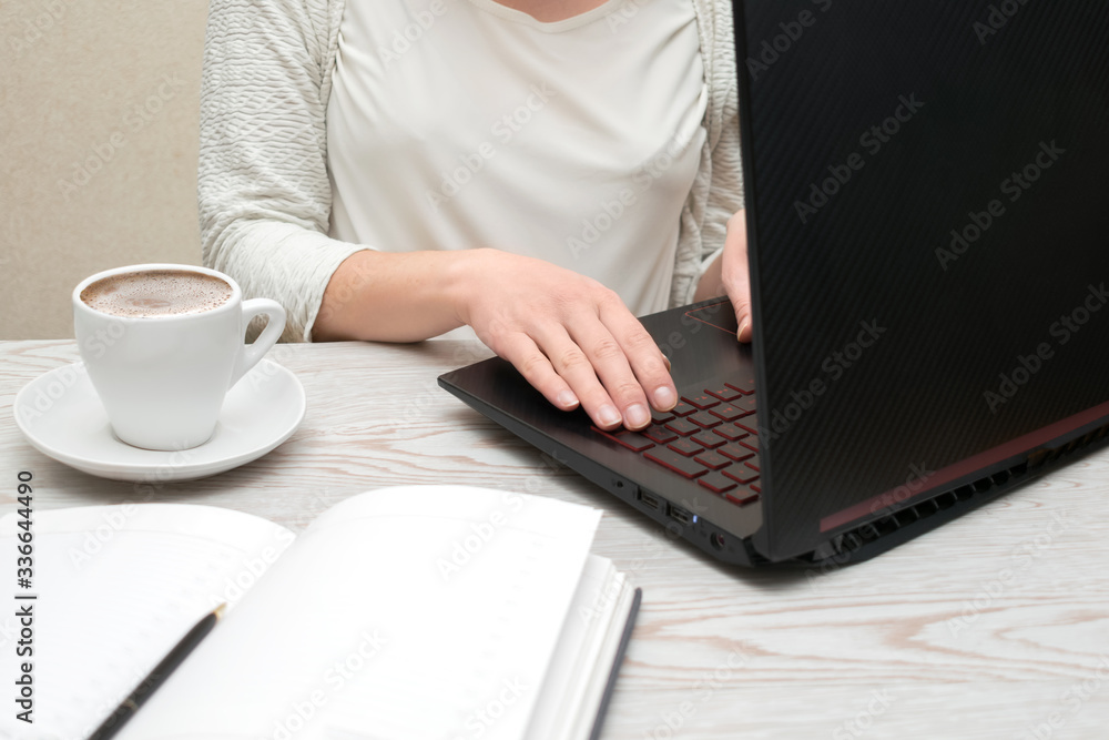 Fototapeta premium Distance learning online education and freelance work. Woman girl working office work remotely from home. Using computer and drinking coffee.