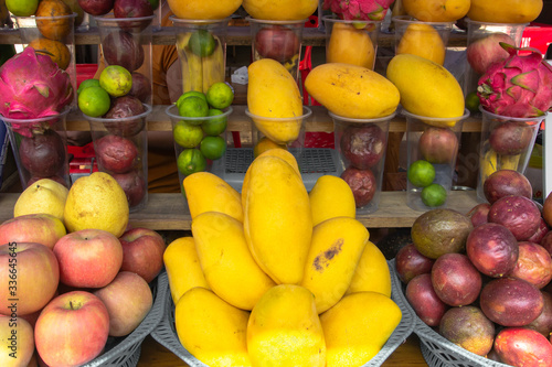 Group of sweet Tropical fruit. Fresh juicy mangos. Fruit background. Mangos  apples and limes at outdoor farmers market in Laos. Close up of variety of fruit. Big assortment of fresh fruit