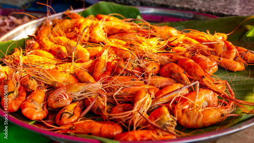 A bunch of small freshly cooked shrimp lie on banana leaves.