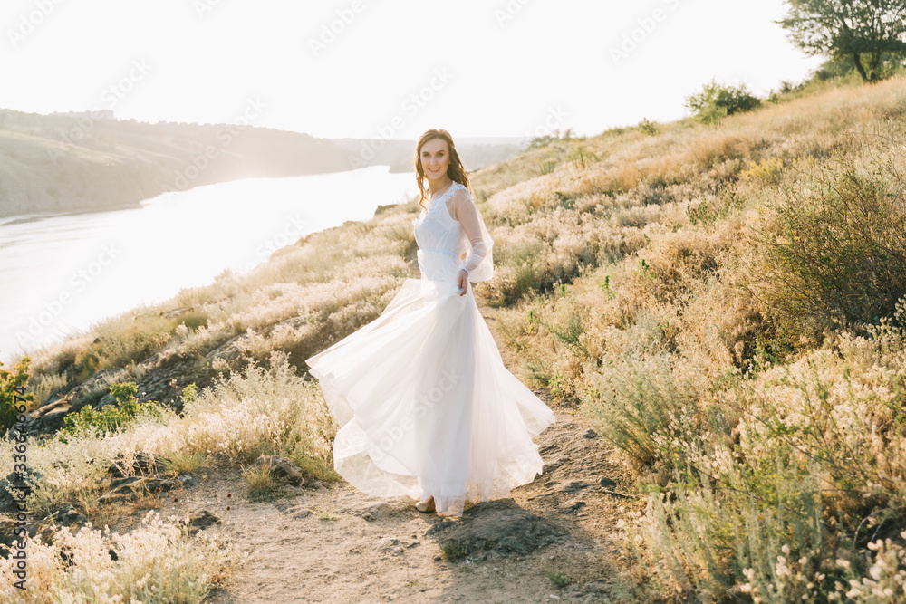 Bride in a luxurious white wedding dress in nature at sunset Bride in a luxurious white wedding dress in nature at sunset