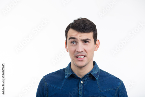 Portrait of unsure, perplexed man. Thoughtful expression of a young man over white background.