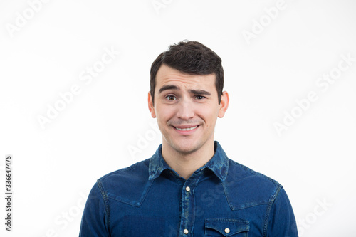 Portrait of unsure, perplexed man with sarcastic smile. Thoughtful expression of a young man over white background.
