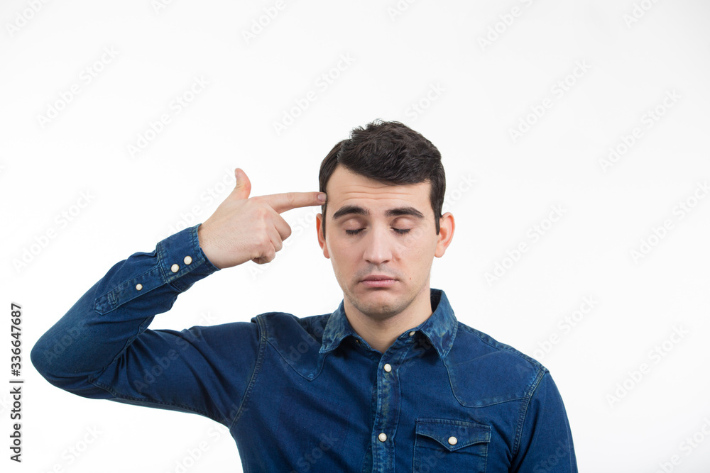 Portrait of stressed man pointing with his finger to his head like a gun. Anxiety expression of a young man over white background. Portrait of stressed man pointing with his finger to his head like a gun. Anxiety expression of a young man over white background.