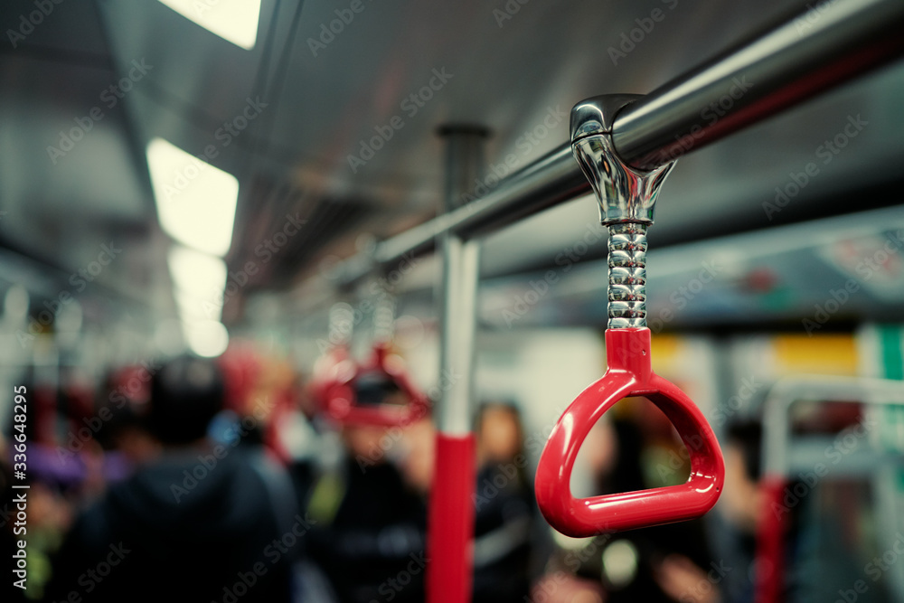 Red hanging handhold for standing passengers in a modern metro train. Suburban and urban transport.