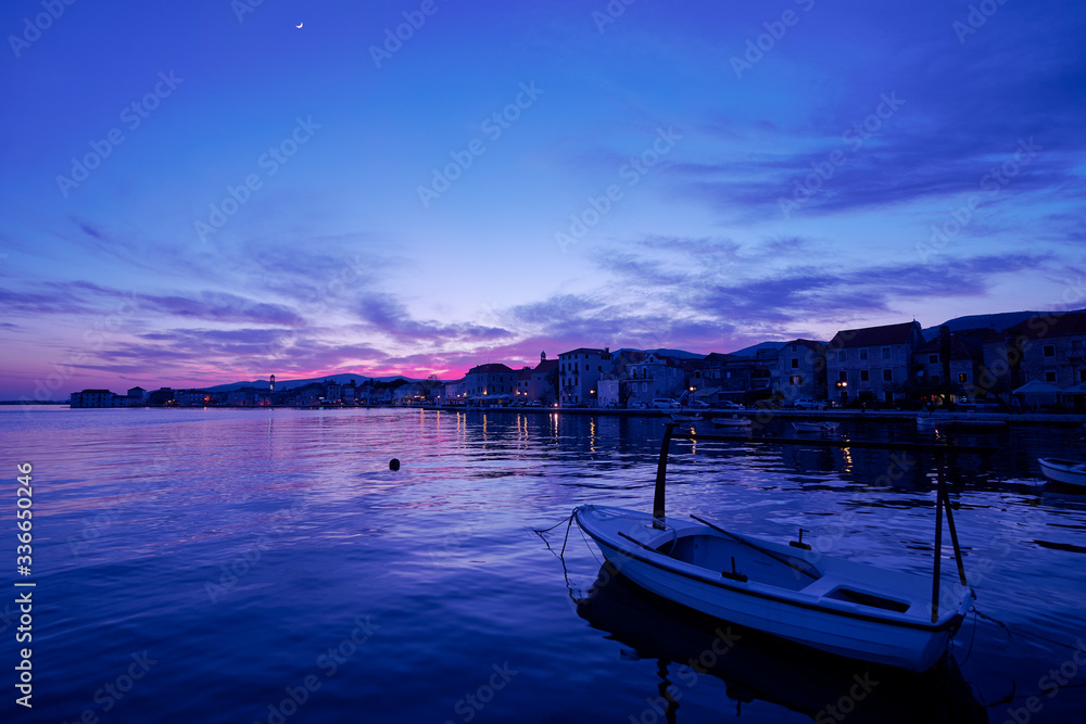 Beautiful sunset landscape. Fishing boat moored on Kastel coast in Dalmatia,Croatia. Old town near Adriatic sea at night.