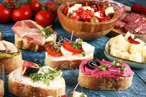 Assorted bruschetta with various toppings. Appetizing bruschetta or crudo crostini. Variety of small sandwiches. Mix bruschetta with tomatoes and basil