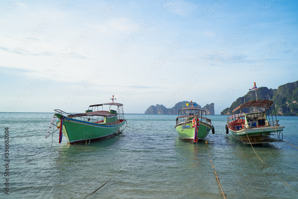 Beautiful tropical landscape with traditional fishing longtail boats on the beach.