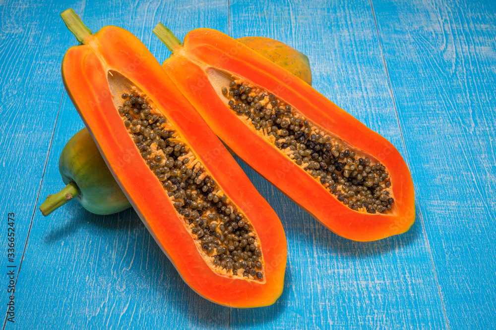 Fresh Papaya fruit, whole and half of ripe papaya fruit with seeds on blue wooden background Fresh Papaya fruit, whole and half of ripe papaya fruit with seeds on blue wooden background