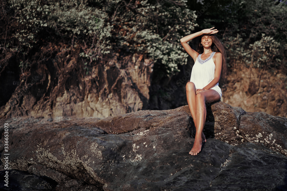 Outdoor portrait of beautiful young woman with long hair sitting on the rock. Outdoor portrait of beautiful young woman with long hair sitting on the rock.
