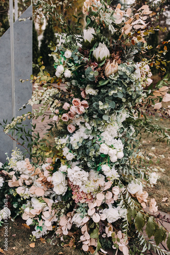 Stylish wedding floristry. The arch for the ceremony is decorated with compositions of flowers and greenery