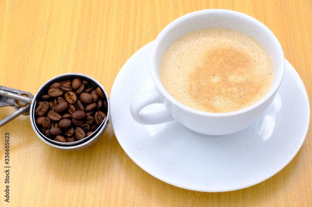 Coffee cup and beans on wooden kitchen table. Top view with morning sunlight Coffee cup and beans on wooden kitchen table. Top view with morning sunlight