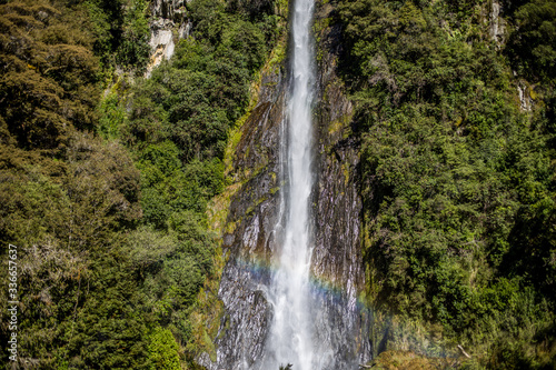 Cachoeira grande cercada por vegetação verde e arco iris