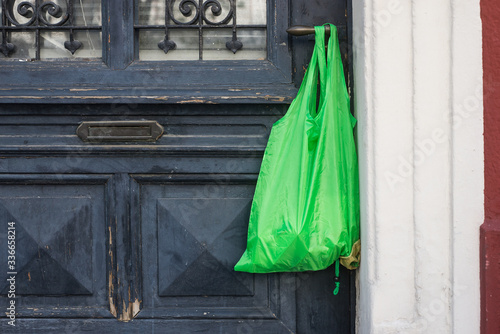 Shopping bag with goods and food  hanging at the handle door to confined people at home , neighborhood help concept at quarantine time during the coronavirus pandemic © pixarno