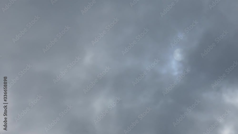 Dark gray and blue clouds rapidly moving on the sky. Blurred light shining through them. Sun in the haze. Bad weather, cloudy day. Natural background. Dark gray and blue clouds rapidly moving on the sky. Blurred light shining through them. Sun in the haze. Bad weather, cloudy day. Natural background.