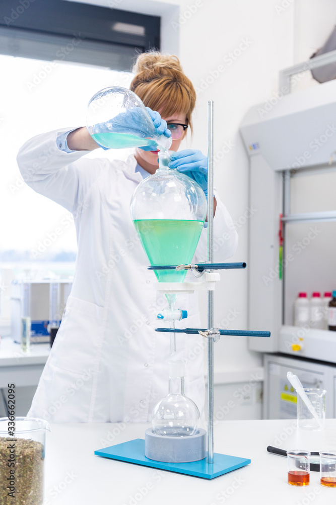 Woman working with green turquoise liquid in separator funnel Woman working with green turquoise liquid in separator funnel