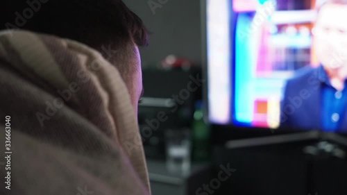 Male in medical mask watching breaking news about coronavirus at home