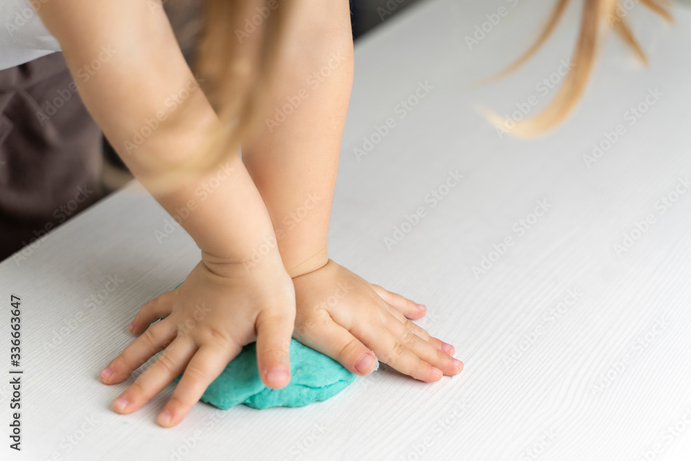 closeup hands of a preschooler child knead turquoise mass for modeling. quarantined children's art