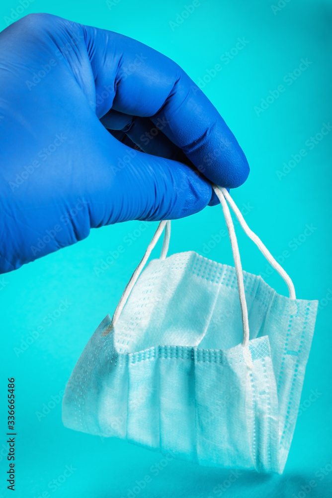 personal protective equipment against viruses and infection. A rubber-gloved hand holds a disposable face mask. Protection from covid-19 coronavirus personal protective equipment against viruses and infection. A rubber-gloved hand holds a disposable face mask. Protection from covid-19 coronavirus