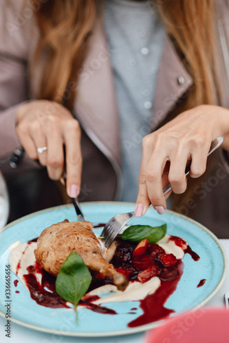 Female hands hold knife and fork, cutting off a piece of chicken.Soft focus