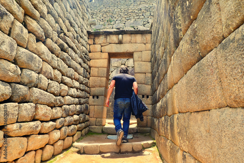 Hombre caminando entre las ruinas de Machu Pichu