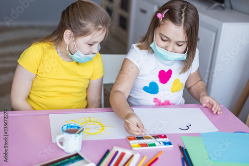 Girls drawing together at home during quarantine in sterile masks. Childhood games  drawing arts  stay at home concept