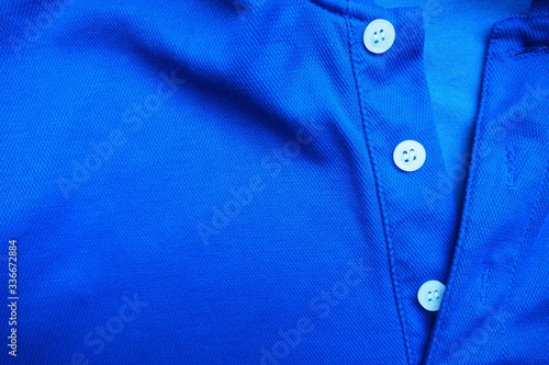 Closeup of new and good quality of bright dark blue shirt with simple white buttons stitched on the placket for modern apparel and beautiful fashion and design concept