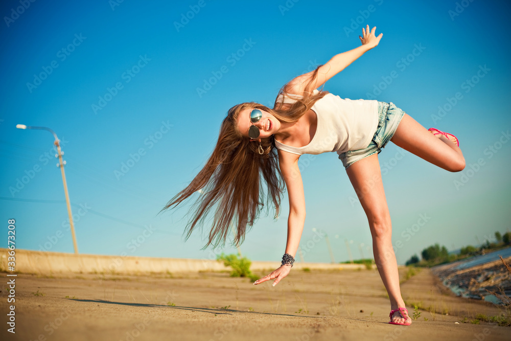 Naklejka premium young woman trying to do cartwheel on the road