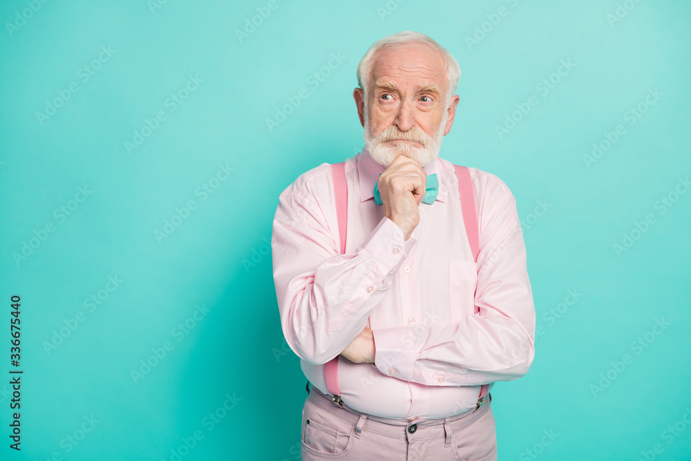 Photo of serious stylish grandpa hold arm on chin look side empty space deeply minded wear pink shirt suspenders bow tie pants isolated bright teal color background