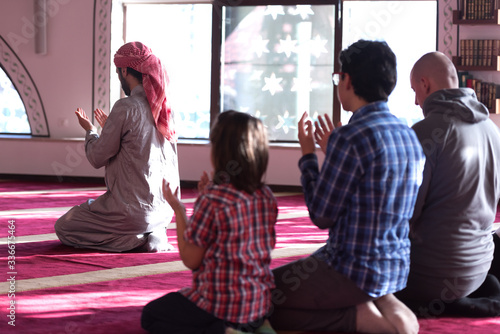 Group of muliethnic religious muslim young people  praying and reading Koran together. Group of muslims praying in the mosque. photo