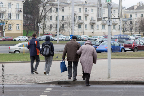 older people, old man and old woman hold hands and cross the street at a pedestrian crossing photo