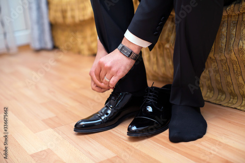 Closeup view of male hands lacing beautiful elegant shoes. wedding day. groom tie his shoe . Man wearing a suit putting his brown shoes on. Hands and shoe close-up.