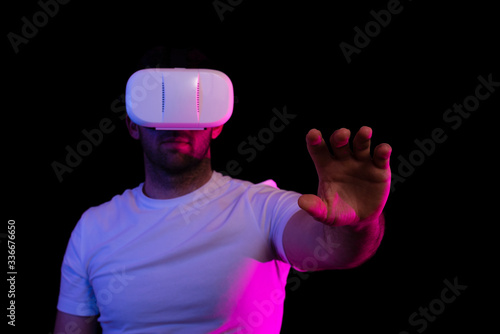 Chico con unas gafas de realidad virtual sobre un fondo negro y colores. Un brazo estirado hacia delante
