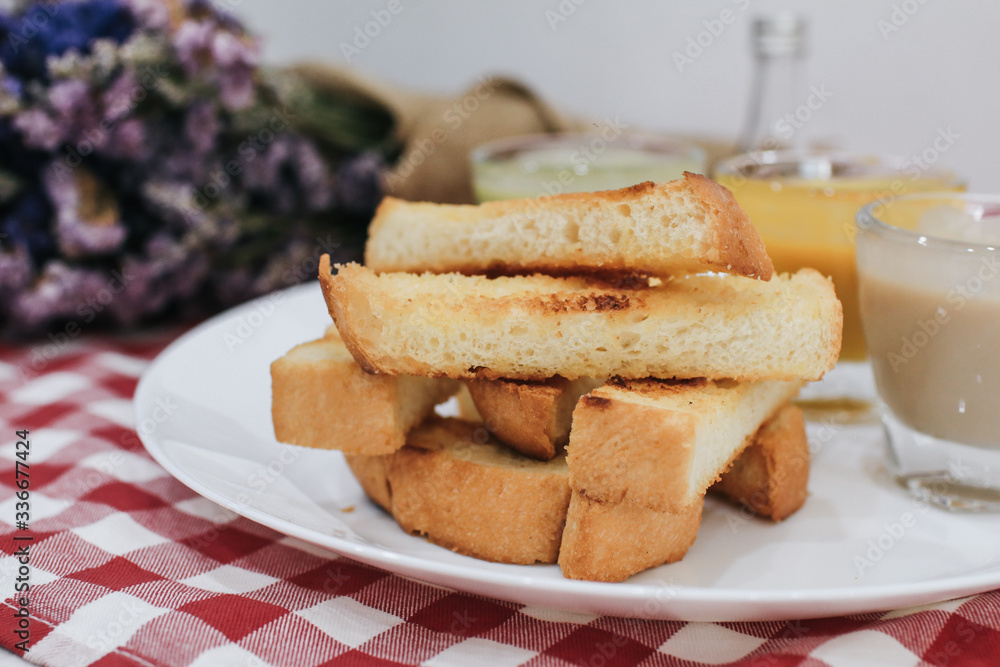 Piece of bread toast with dipping sauce on white plate.Thai Pandan mixed milk custard Custard & grilled bread. Bread with thai pandan custard Thai called Kanom Pang Sang Ka Ya. Piece of bread toast with dipping sauce on white plate.Thai Pandan mixed milk custard Custard & grilled bread. Bread with thai pandan custard Thai called Kanom Pang Sang Ka Ya.