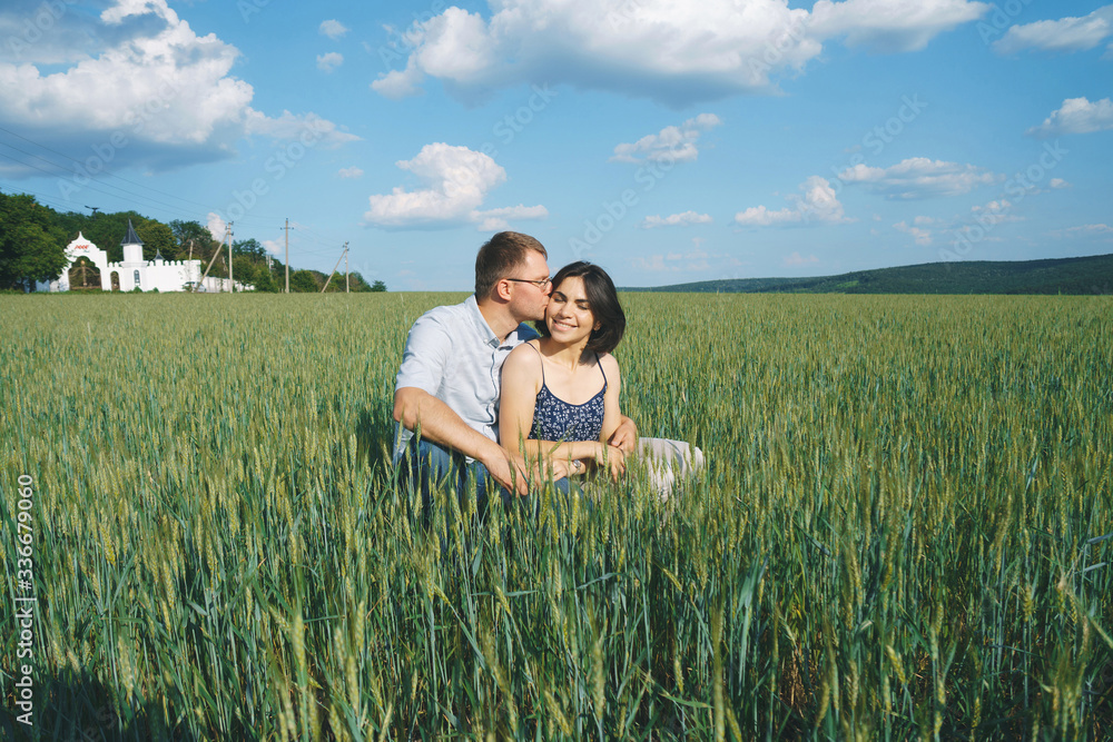 man kissing woman in cheek in grass man kissing woman in cheek in grass