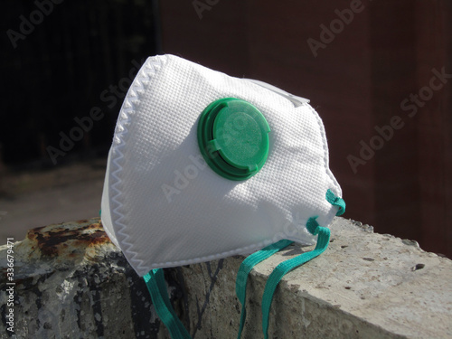 Respirator with a valve on the concrete balcony of an abandoned building. Pandemic covid 19. Coronavirus. White respirator on grunge background. The concept of survival in extreme conditions. photo