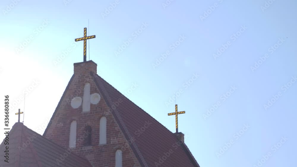 Looking up at the rooftop of the Zapyskis Gothic church with three crosses on the roof backlit by the sun Looking up at the rooftop of the Zapyskis Gothic church with three crosses on the roof backlit by the sun