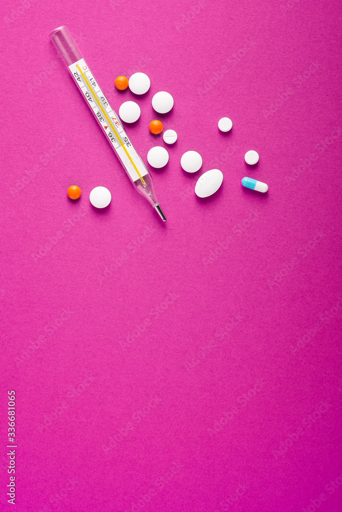 Pills, tablets and analog thermometer on pink purple background, healthcare medical concept, antibiotics and cure, top view copy space Pills, tablets and analog thermometer on pink purple background, healthcare medical concept, antibiotics and cure, top view copy space