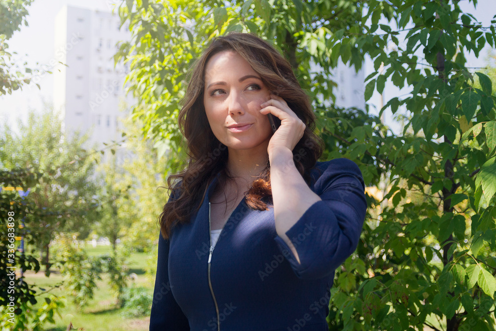 Beautiful business woman talking on a smartphone in the park. People Beautiful business woman talking on a smartphone in the park. People