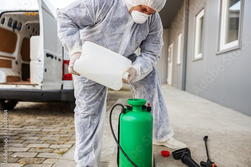 Specialist in hazmat suits preparing for cleaning and disinfecting coronavirus cells epidemic, world pandemic health risk.