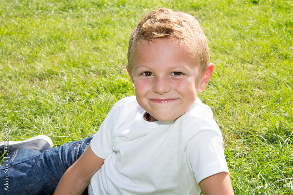 portrait of cute little blonde boy lying on home garden grass park portrait of cute little blonde boy lying on home garden grass park