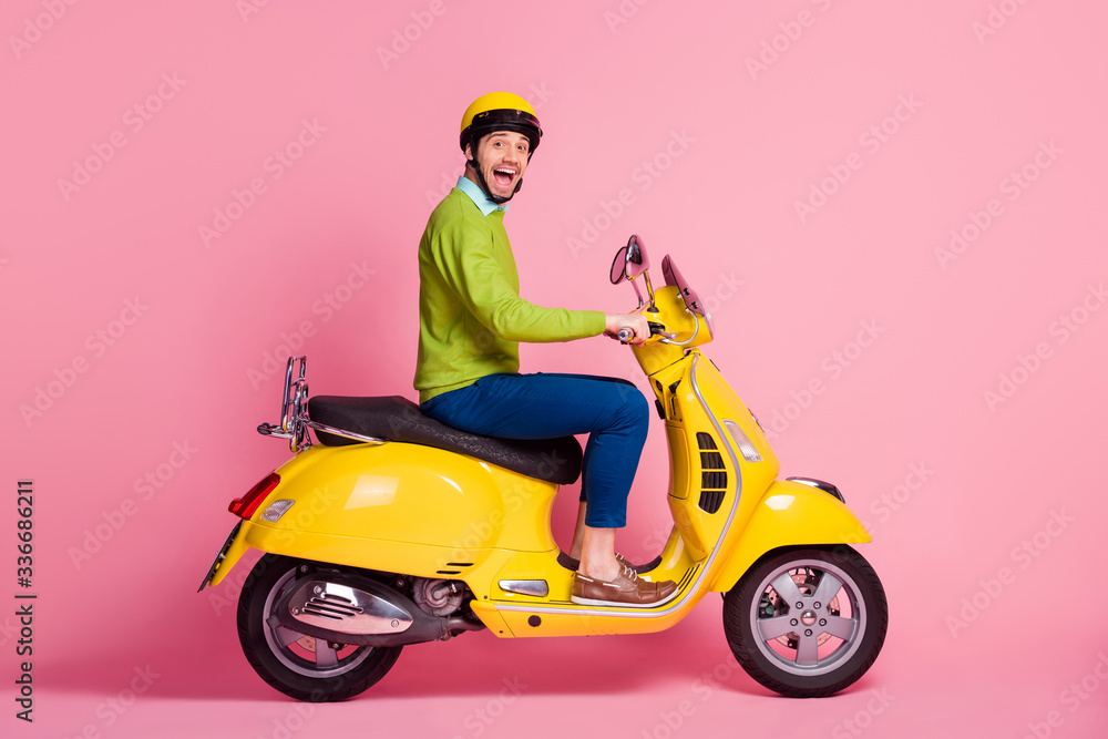 Profile side view portrait of his he nice attractive crazy overjoyed glad cheerful cheery guy driving moped having fun traveling isolated over pink pastel color background