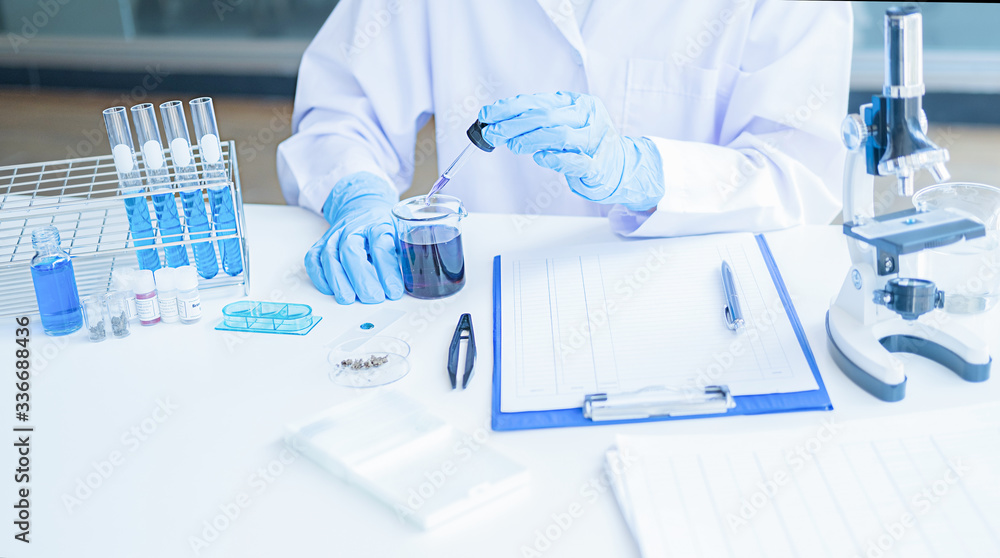 Medical or scientific researcher or man doctor looking at a test tube of clear solution in a laboratory Medical or scientific researcher or man doctor looking at a test tube of clear solution in a laboratory
