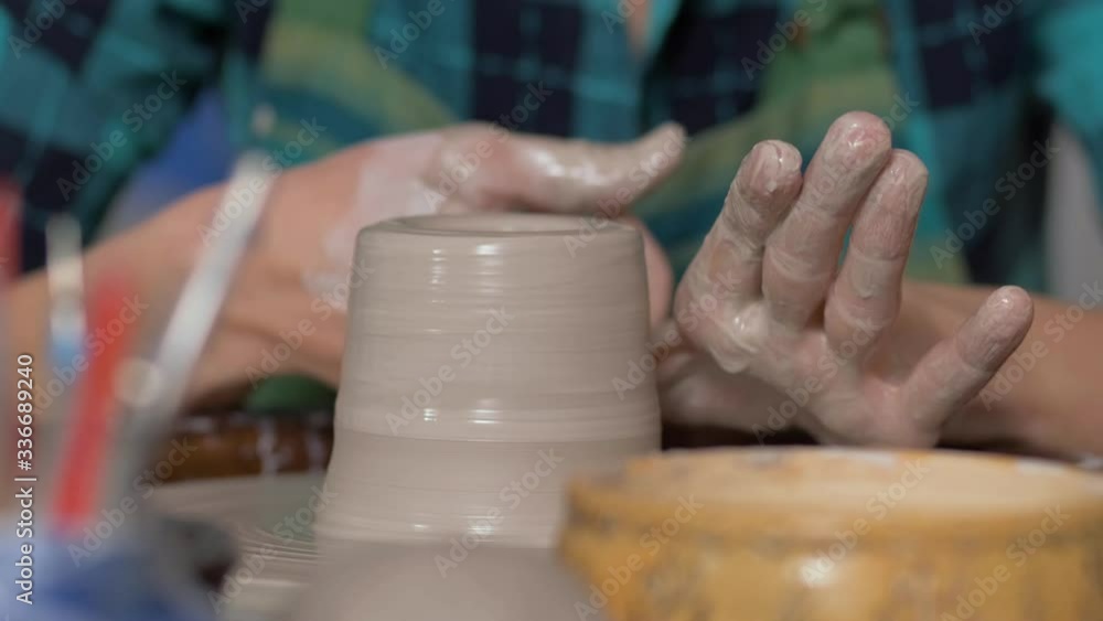 Side view. The product revolves on a pottery wheel. The girl's hand. Life Cup on a pottery wheel. Wetting the clay with water Side view. The product revolves on a pottery wheel. The girl's hand. Life Cup on a pottery wheel. Wetting the clay with water