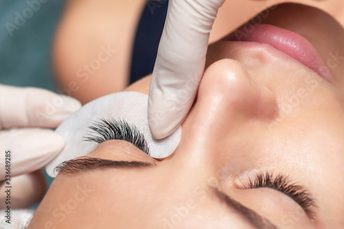 Young woman receiving extending the eyelashes in a beauty salon, close up, eyelash extension procedure.