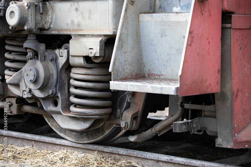 Low angle view of wheel mechanism of modern train locomotive on tracks. Steampunk, techno, power concept. Railroad transport, iron or steel constructions, wagon part, chassis. Transport industry