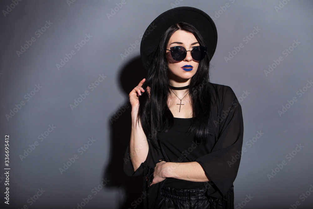 Gothic caucasian woman in dark dress on a grey neutral background. Contrast light. Sad, thoughtful emotions Gothic caucasian woman in dark dress on a grey neutral background. Contrast light. Sad, thoughtful emotions