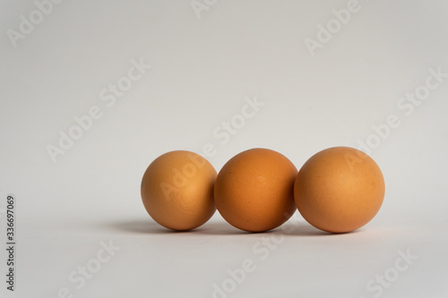 Three fresh brown chicken eggs in a row on grey background. Easter holiday