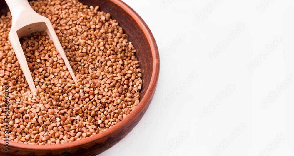 Buckwheat in a clay bowl close-up on a white background. Copy space. Banner Buckwheat in a clay bowl close-up on a white background. Copy space. Banner