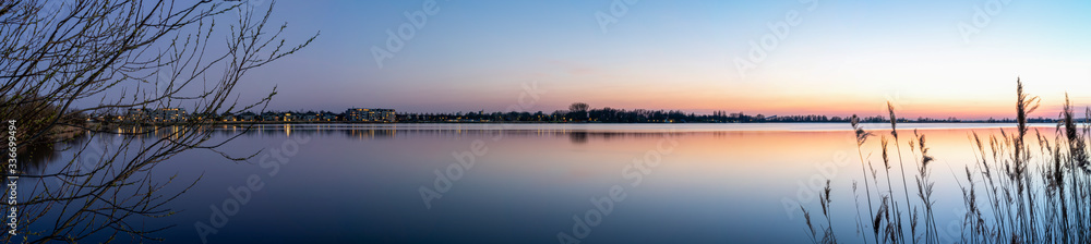 A panorama photo during the Blue hour on a allmost windless evening with a smooth lake Zoetermeerse Plas, Netherlands